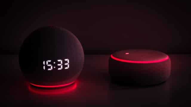 Zwei Alexa Geräte die rot leuchten mit dunklem Hintergrund.