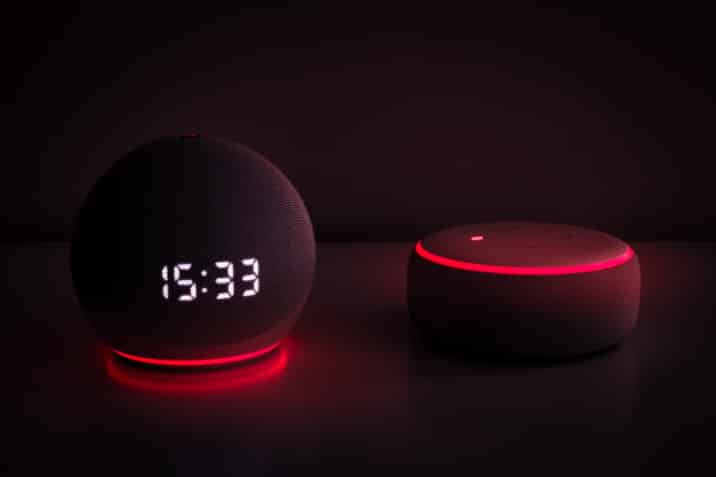 Zwei Alexa Geräte die rot leuchten mit dunklem Hintergrund.